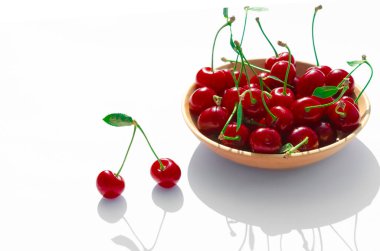 Beyaz arka planda yeşil yapraklı kırmızı sulu kiraz.