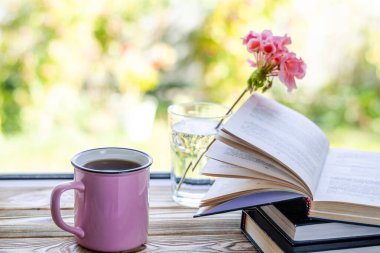 Pembe bir fincan çay, ahşap bir pencere pervazında durur.