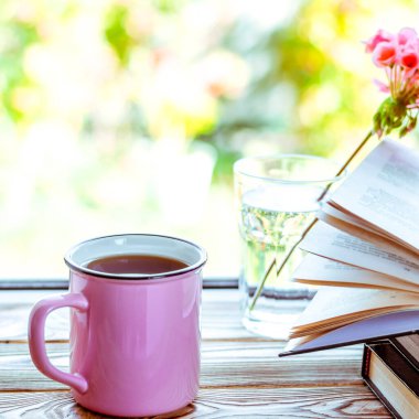 Pembe bir fincan çay, ahşap bir pencere pervazında durur.