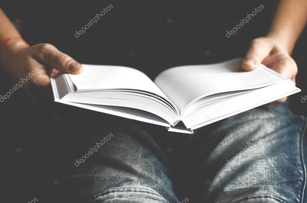 Cozy concept. A man in blue jeans holds a mock white clean book