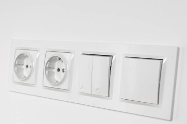 Beyaz plastik anahtarlar ve beyaz bir duvardaki prizler. Onarım