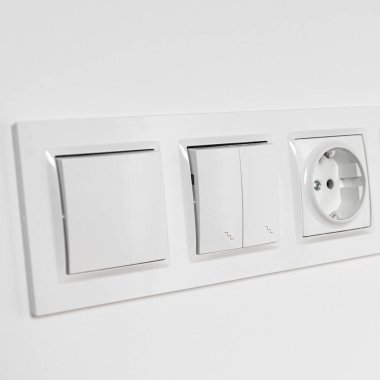 Beyaz plastik anahtarlar ve beyaz bir duvardaki prizler. Onarım