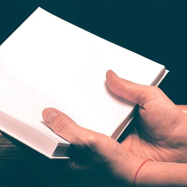 Un modello di un libro bianco con un posto per il testo nelle mani di un uomo su un tavolo — Foto Stock