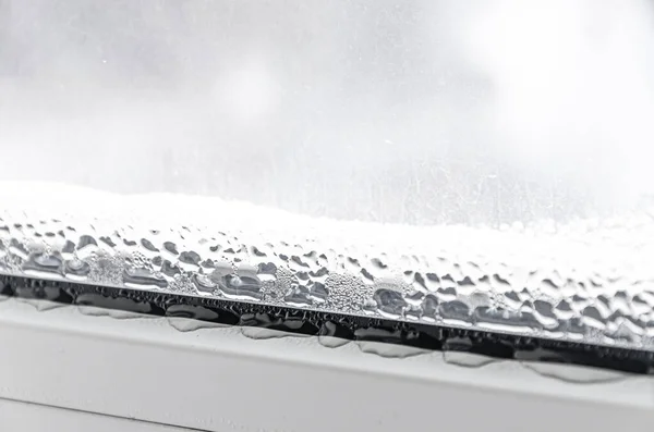 Beyaz plastik bir pencerede siyah küf ve yoğunlaştırılmış damlalar. Yakın plan.