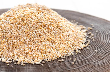 İnci arpalı çuval bembeyaz bir zemin üzerine dökülüyor.