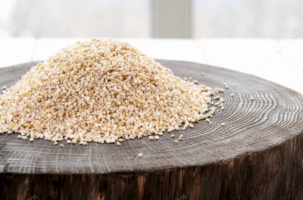 Burlap sack with pearl barley spilling out over a white background