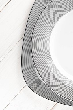 Beyaz yuvarlak, klasik, gri desenli porselen plakalar beyaz ahşap bir masa üzerinde duruyor.