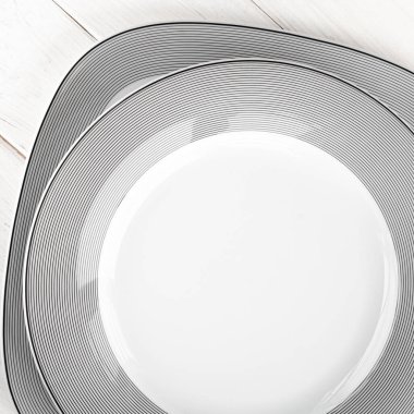 Beyaz yuvarlak, klasik, gri desenli porselen plakalar beyaz ahşap bir masa üzerinde duruyor.