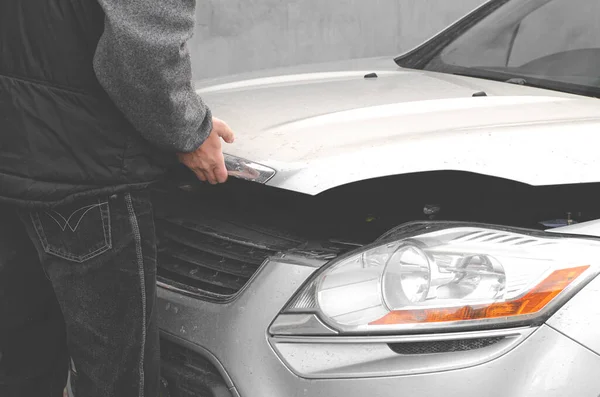 Man opens car bonnet for engine inspection