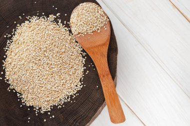 İnci arpalı çuval bembeyaz bir zemin üzerine dökülüyor.