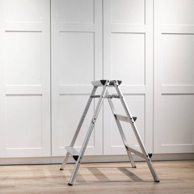 Mobilya onarımı ve montajı için katlanan merdiven ahşap bir zeminde duruyor. Onarım