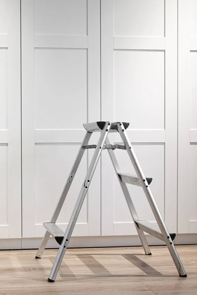 Mobilya onarımı ve montajı için katlanan merdiven ahşap bir zeminde duruyor. Onarım
