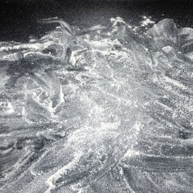 Beyaz fırın unu siyah masanın üzerine tozlanmış. Arkaplan