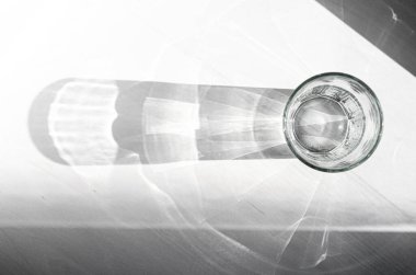 Saf, berrak eritilmiş suyu olan bir bardak beyaz bir ahşap masanın üzerinde duruyor.