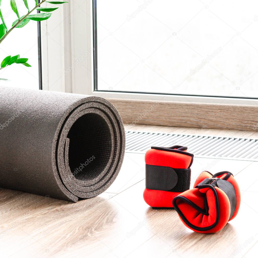 A sporty concept. A healthy lifestyle. Fitness mat and weights for arms and legs