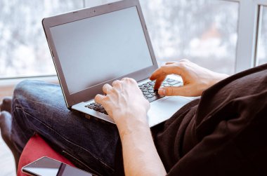 Uzaktan öğrenme, izolasyon, iş, online alışveriş kavramı. Uzaktan kumanda evden çalışıyor. Mutfakta dizüstü bilgisayarlı serbest çalışan biri. Erkek ellerine yakın dur..