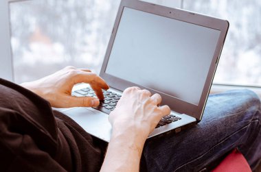 Uzaktan öğrenme, izolasyon, iş, online alışveriş kavramı. Uzaktan kumanda evden çalışıyor. Mutfakta dizüstü bilgisayarlı serbest çalışan biri. Erkek ellerine yakın dur..