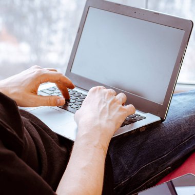 Uzaktan öğrenme, izolasyon, iş, online alışveriş kavramı. Uzaktan kumanda evden çalışıyor. Mutfakta dizüstü bilgisayarlı serbest çalışan biri. Erkek ellerine yakın dur..