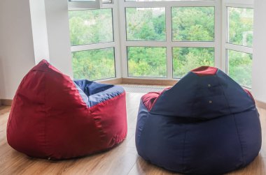 Yumuşak ve rahat puf minderler panoramik pencerenin yanında yerde duruyor. İç mekan