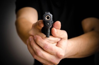 Atış menziline nişan alan adam. Elinde silahla ateş etmeye hazır bir adam var. Hırsız ya da haydut konsepti.