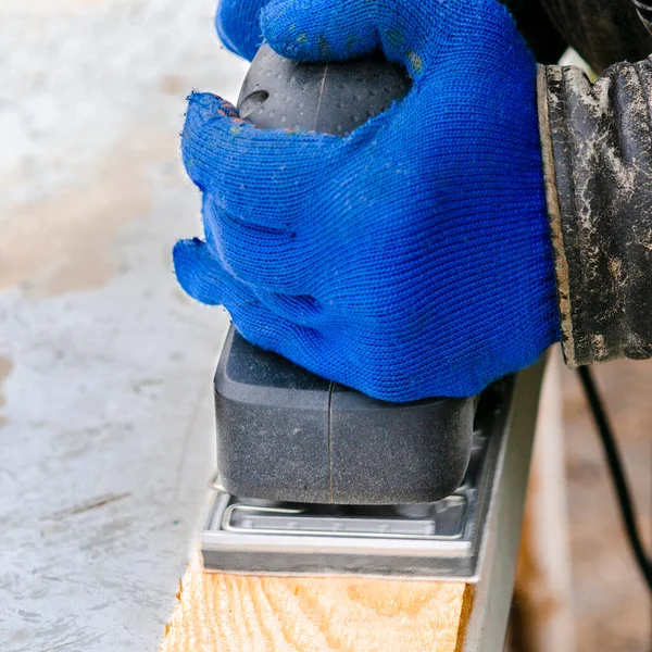 Working with a grind machine. Men\'s hands in blue gloves work with power tools