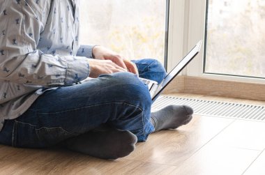 Uzaktan öğrenme, izolasyon, iş, online alışveriş kavramı. Uzaktan kumanda evden çalışıyor. Mutfakta dizüstü bilgisayarlı serbest çalışan biri. Erkek ellerine yakın dur..