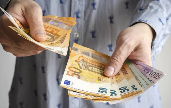 Adam parayı elinde tutuyor. Ödeme ya da takas için euro olarak nakit. Erkek, euro banknotlarında maaşı sayar. Para biriktirmek, banka depozitosu çekmek. Avrupa parası. Ekonomik kriz