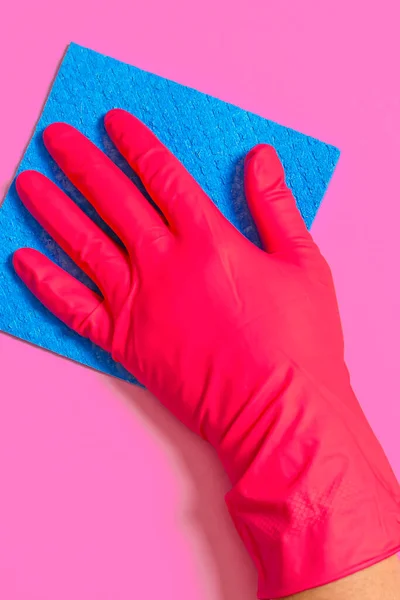 Niebieski dom mycie gąbka w dłoni w czerwonej gumowej rękawicy na różowym tle — Zdjęcie stockowe