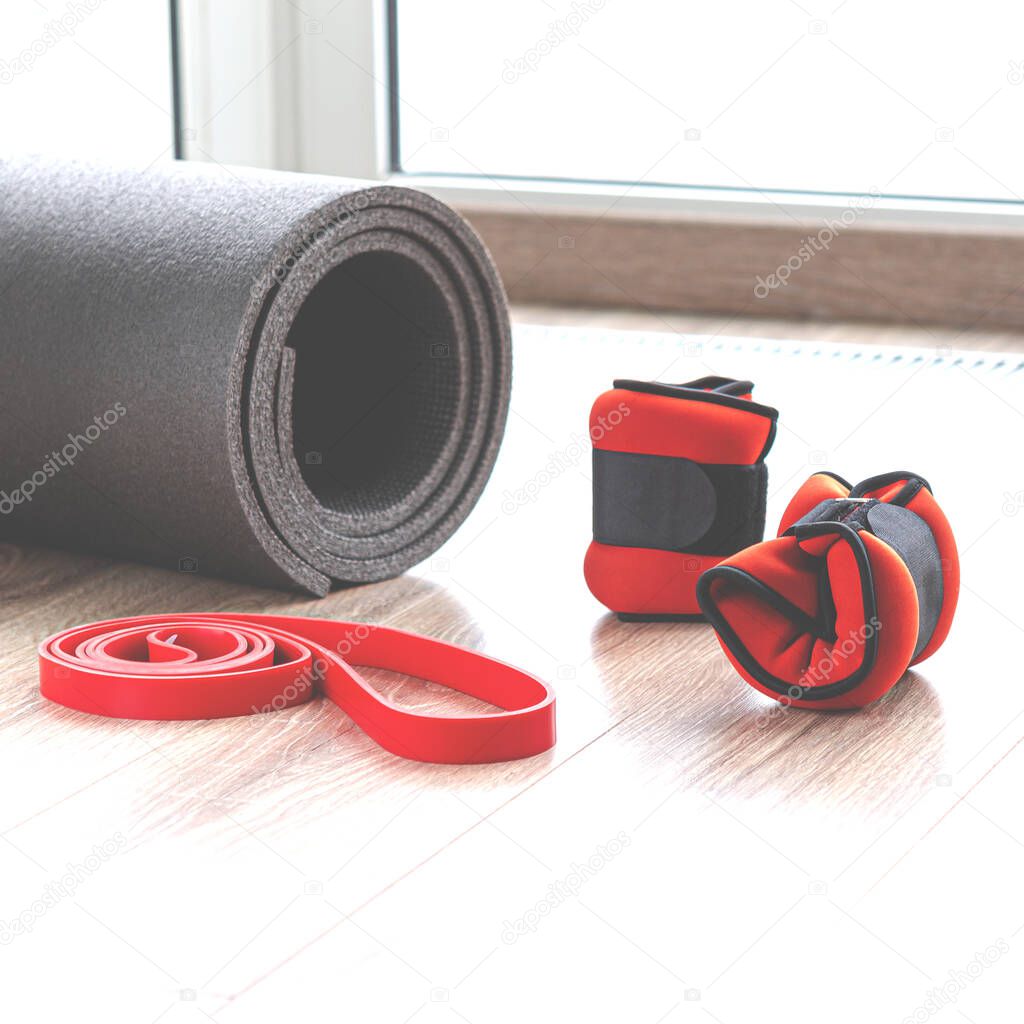 Sports content. Fitness mat, pull-up rubber, leg weights lie on the gym floor