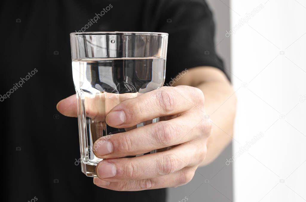 A glass of pure melt water in a mans hand. Water balance