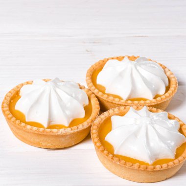 Limonlu pasta. Beyaz zemin üzerinde limon kremalı ve kabarık kremalı küçük limonlu pasta ve kabarık kremalı pasta. Seçici odak.