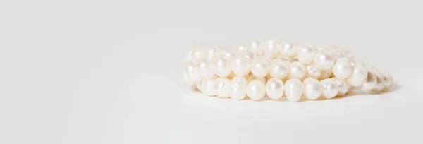 Una pancarta con un collar de perlas envuelto en un enredo sobre un fondo blanco. — Foto de Stock