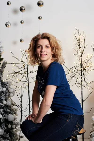 Fiatal Szőke Göndör Kék Pólóban Díszített Fal Előtt Karácsonyfákkal Fényekkel — Stock Fotó