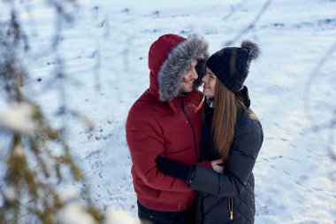 Birbirine aşık genç bir çift, dışarıda kar parkı ormanında kış havasının tadını çıkarıyorlar. Kırmızı ceketli adam siyahlı kadına sarılıyor. Noel ve yeni yıl tatili neşesi. Romantik randevu, ilişki.