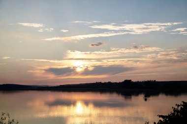 Gün batımında göl manzarası çok güzel. Suda mavi ve sarı gökyüzü yansıması var. Kırsal alan. Ekolojik koruma ve ekolojik turizm konsepti. Doğa manzarası. Kırsal bölgede izolasyon.