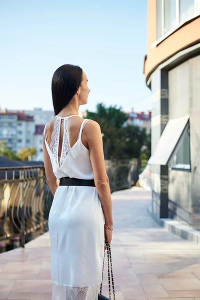 Mulher Morena Jovem Vestindo Vestido Branco Seda Segurando Bolsa Preta — Fotografia de Stock