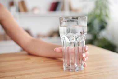 Ofis masasında çalışan, iş yerinde müdürlük yapan, elinde su olan genç bir kadının yakın plan fotoğrafı. Şirkette çalışma süreci. Sağlıklı içecek tüketimi kavramı. Su dengesi..