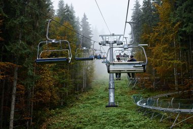 Sonbaharda yeşil ormanın ortasında kayak kaldırma gezisi. Dağlar bulutlu bir sonbahar gününde sisle kaplıdır. Doğal çevreye kaçış tatili. Dağ Tatil Köyü.