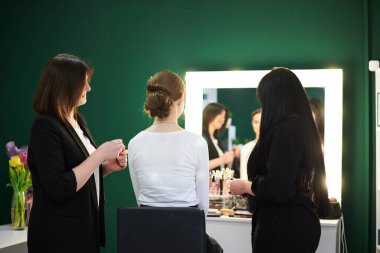 Partiye hazırlanıyorum. Kuaför ve makyöz onu güzelleştirirken güzellik salonunda oturan genç ve güzel bir kız. Stüdyoda profesyonel çalışma süreci. Kendini sev. Gelinin sabahı.