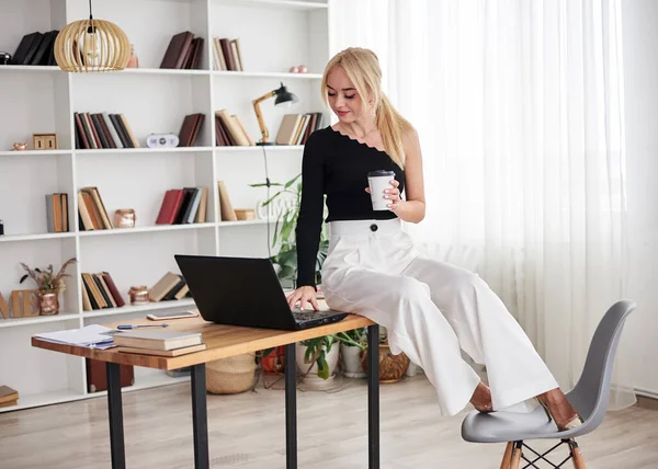 Young Blond Woman Wearing Black Top White Pants Sitting Table Stock Picture