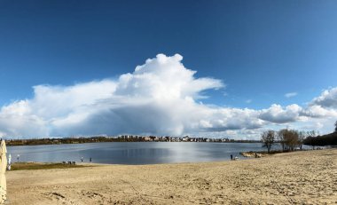 Mavi suya yansıyan bulutlarla gölün manzarası. Baharın aydınlık tazeliği. Köydeki huzurlu gölet. Meditasyon tekniği. Kırsal kesimde güneşli bir hava. Çevre koruma