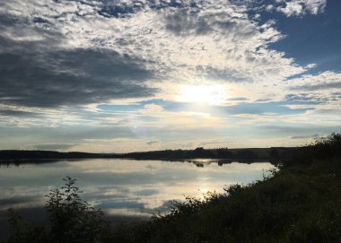 Gölün şeffaf suları üzerinde güzel bir günbatımı. Uzak bir yere git. Çevreyi koru, Dünya gezegeni. Kristal berrak suda bulutların yansıması. Nefes kesici manzara..