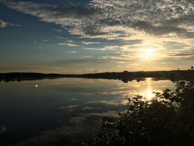 Akşamları gölün üzerinde güzel bir günbatımı. Kırsal kesimde sakin bir manzara. Doğada derin meditasyon. Fotoğraf için sihirli bir loş ışık saati. Gölün panoramik manzarası.