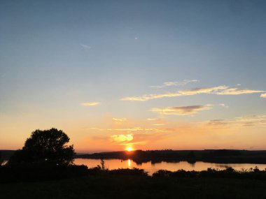 Kırsal alanda gün batımının muhteşem manzarası. Mavi mor gökyüzünde pembe mor bulutlar. Kırsalda sakin bir akşam. Büyülü atmosfer meditasyon ve rahatlama için mükemmeldir..