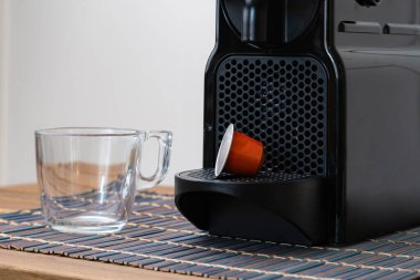 Evdeki kahve makinesinin yanında hayat ferahlatıcı espresso kapsülü ve fincanı duruyor. Kimse.