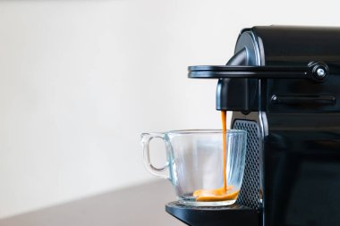 Kapsül makinesinin ferahlatıcı espresso 'sunu evdeki bir bardağa boşalt. Kahve molası kavramı.