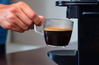 Evdeki kahve makinesinden bir fincan espresso almak için elinizi kaldırın. Kahve molası kavramı.