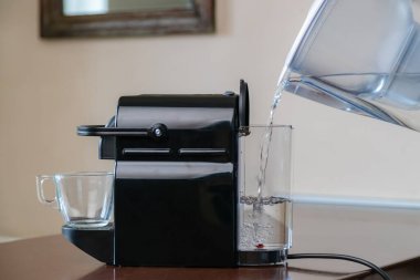 Saf filtrelenmiş suyu kapsül kahve makinesine dök..