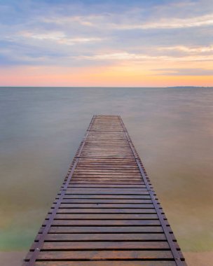 Göl kıyısındaki Idyllic köstebek (iskele). Baharda tahta köprü ve gün doğumunda mavi göl. Rıhtımda balık tutmak için göl