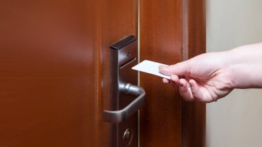 Kadın, otel odasının kapısını açmak için anahtar kartı takıyor. Kapı erişimi için manyetik kart tutuluyor. Kapıyı kilitleyip açmak için anahtar kartı taranıyor.